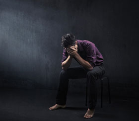 Person sitting with head bowed, representing low mood